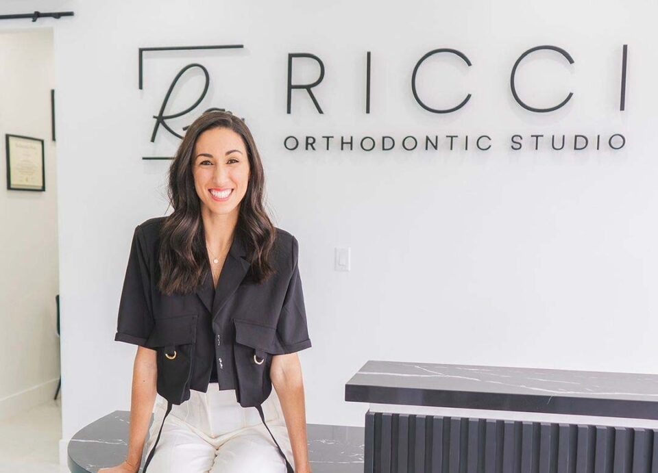 Dr. Alyssa Ricci sitting on the desk in her practice's lobby